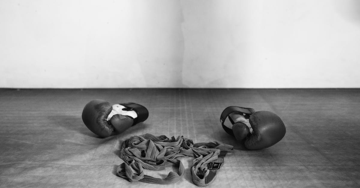 Black-and-white shot of boxing gloves and wraps on the gym floor, embodying a minimalist sports theme.